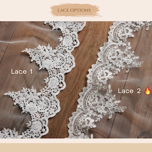 Puede incluir: Dos tiras de encaje floral blanco etiquetadas como Lace 1 y Lace 2. El encaje presenta un bordado intrincado con bordes festoneados y delicados patrones de hojas sobre una base de tul transparente. El texto LACE OPTIONS es visible arriba.