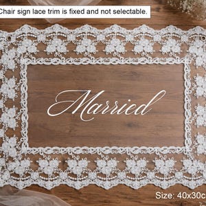 Puede incluir: Un letrero rectangular de encaje blanco de 40x30 cm con un patr&oacute;n floral y la palabra Married en letra cursiva blanca. El texto Chair sign lace trim is fixed and not selectable es visible en la parte superior.