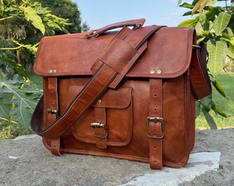 May include: A brown leather messenger bag with a front pocket and two buckles on each side. The bag has a long adjustable strap and a top handle.