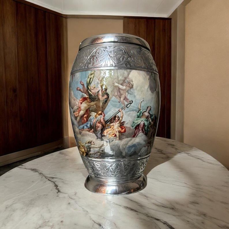 May include: A silver vase with an ornate design and a painted scene of figures in the clouds. The vase has a round body and a wide base.