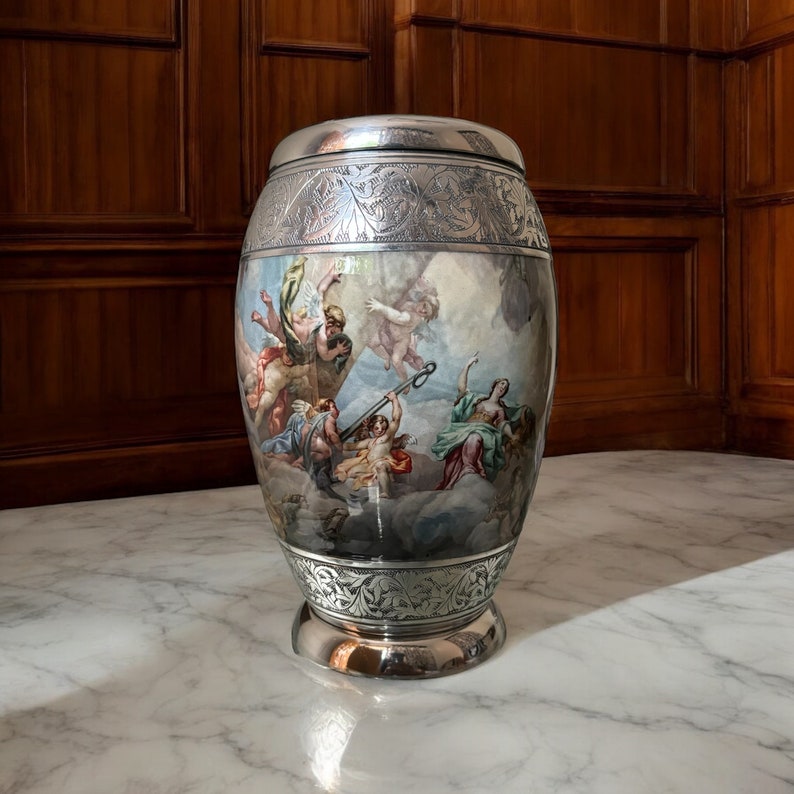 May include: A silver urn with an ornate design and a painted scene of figures in the clouds. The urn has a round body and a wide base.