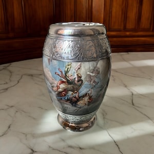 May include: A silver urn with an engraved design and a painted scene of angels in the clouds.