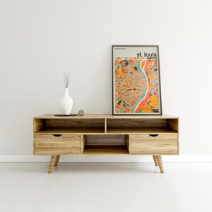May include: A wooden entertainment center with two drawers and open shelves. A framed print of a colorful map of St. Louis, Missouri is on top of the entertainment center.