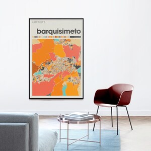 May include: A framed print of a colorful map of Barquisimeto, Venezuela. The map is in a black frame and is hanging on a white wall. The map is surrounded by a light brown floor and a gray couch.