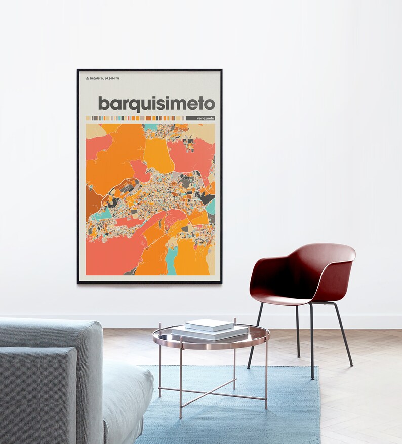 May include: A framed print of a colorful map of Barquisimeto, Venezuela. The map is in a black frame and is hanging on a white wall. The map is surrounded by a light brown floor and a gray couch.