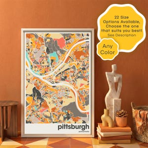 Op de afbeelding: Een ingelijste kaartprint van Pittsburgh, Pennsylvania, in een moderne, abstracte stijl. Het kunstwerk heeft een levendig kleurenpalet van oranje, geel, grijs en blauwgroen. De stadsnaam staat in het wit onderaan. Tekst op de afbeelding zegt "22 maten beschikbaar, kies degene die het beste bij u past! Zie beschrijving" en "Elke kleur".