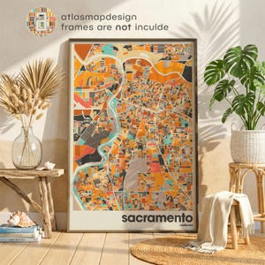 May include: A framed map print of Sacramento, California, featuring a colorful abstract design in shades of orange, teal, and gray. The city name is displayed in a bold, sans-serif font at the bottom. The text "atlasmapdesign frames are not inculde" is in the upper left corner.