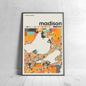 May include: A colorful map of Madison, Wisconsin, with the city name and coordinates in the top left corner. The map is in a black frame and is on a white wooden floor.