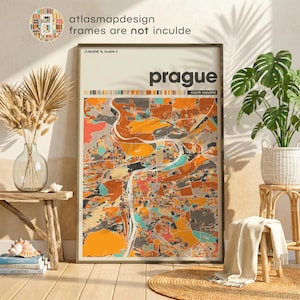 May include: A framed map print of Prague, Czech Republic, featuring a colorful abstract design in shades of orange, gray, and teal. The city name is displayed in bold letters, with the country below. The print is displayed in a room with natural decor.