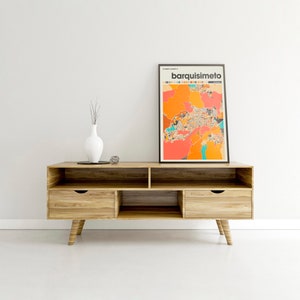 May include: A wooden entertainment center with three shelves and two drawers. A framed print of a colorful map of Barquisimeto, Venezuela is displayed above the entertainment center.