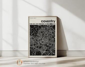 May include: A framed black and white map of Coventry, England. The map features a detailed street layout and is labeled with the city's name in a bold font. The frame is a light wood color, and the print is displayed against a white wall.