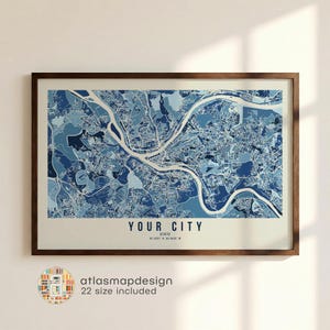 May include: A framed map print in varying shades of blue, showing a city's infrastructure, including roads and rivers. The text "YOUR CITY" is at the bottom, with coordinates. The print is encased in a dark brown wooden frame.