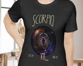 May include: Black t-shirt with a gold and white graphic of a scorpion in a circle with a galaxy background. The text "Scorpio" is above the graphic and the dates "Oct 23rd" and "Nov 21st" are below the graphic. The scorpion zodiac symbol is below the dates.