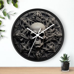 May include: A black clock with a white skull and intricate, detailed, gray, 3D design. The clock face is surrounded by a circular, black frame.