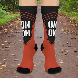 May include: A pair of orange and black socks with the word "ON ON" printed on the front of each sock.