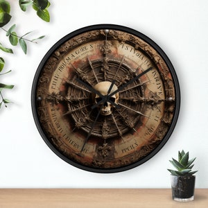 May include: A black and white clock with a skull in the center. The clock face is surrounded by a circular design with text in a gothic font. The text reads "FIVTH TOU MA A CURE S", "ISTVOIA DI INVIDIA", "DI JAVANTI LI FIERN ME", and "PPCILS".
