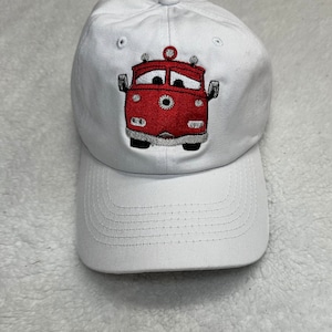 May include: White baseball cap with an embroidered red fire truck with a face on it.