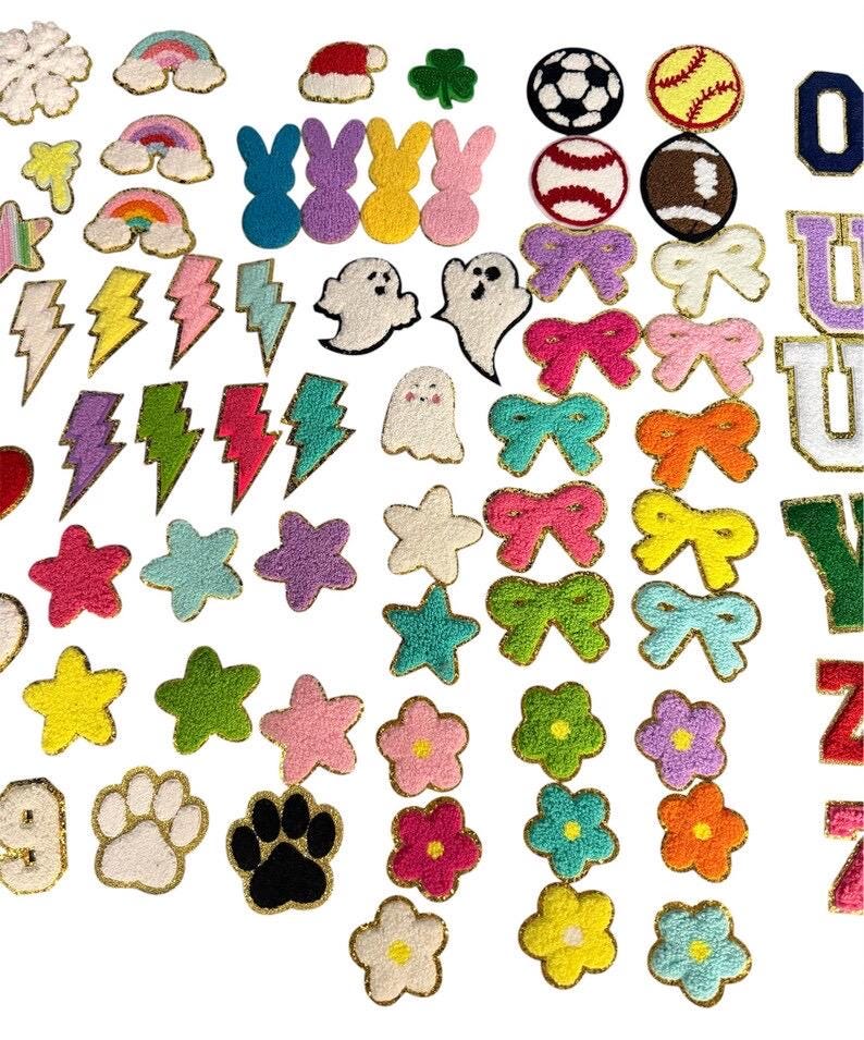 May include: A collection of assorted chenille patches featuring various shapes including rainbows, lightning bolts, stars, ghosts, bunnies, sports balls, bows, flowers, paw prints, and letters, all with gold glitter borders for fabric application.