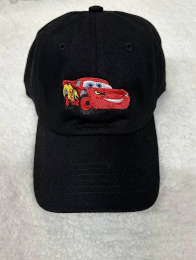 May include: Black baseball cap with an embroidered image of a red race car with a yellow lightning bolt on the side. The car has a smiling face.
