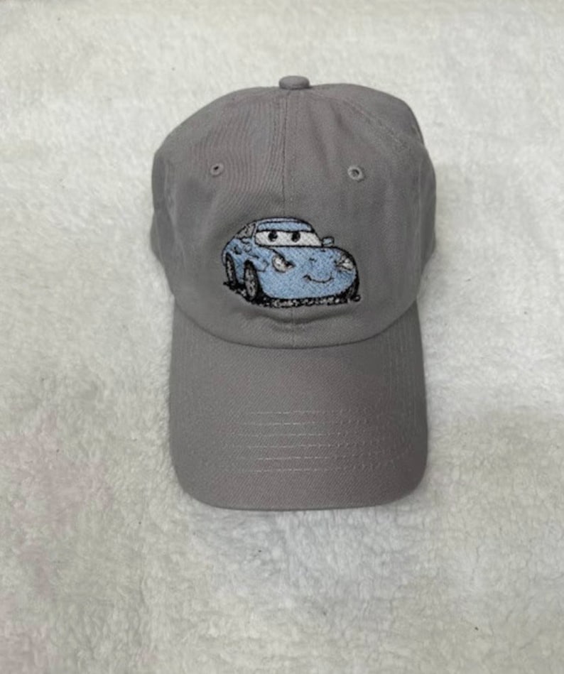 May include: A gray baseball cap with a blue cartoon car embroidered on the front.