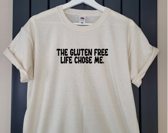 May include: A white t-shirt with black text that reads "THE GLUTEN FREE LIFE CHOSE ME."