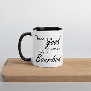May include: White ceramic mug with a black rim and handle. The mug has black text that reads "There is a good chance this is Bourbon".