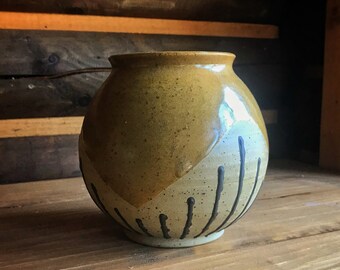 May include: A ceramic vase with a brown, white, and black geometric design. The vase has a rounded body and a wide opening.