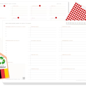 Puede incluir: Un conjunto de planificadores blancos con texto naranja y pegatinas de puntos rojos. Los planificadores incluyen diseños anuales y semanales, con secciones para notas y proyectos. También se incluye una etiqueta con la bandera alemana y el texto "Made in Germany".