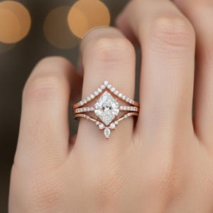 Peut inclure: Un ensemble de bagues de fian&ccedil;ailles en or rose, comprenant une bague principale avec un diamant central de taille marquise. L'ensemble comprend une alliance sertie de diamants et une bague en forme de chevron. Les bagues sont orn&eacute;es de petits diamants.