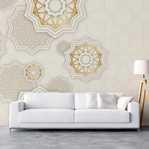 May include: A white sofa with a white throw pillow sits in front of a wall with a geometric pattern in gold and white. The pattern is made up of overlapping stars and circles.
