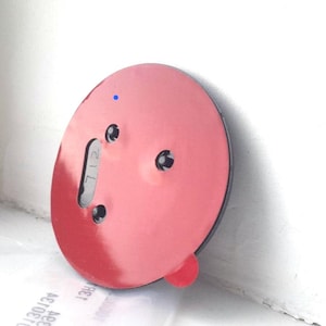 May include: A round, red suction cup with a black rim and three small holes. A small, red tab is visible on the side. The number "712" is printed on a gray tab. A small blue dot is visible on the surface.