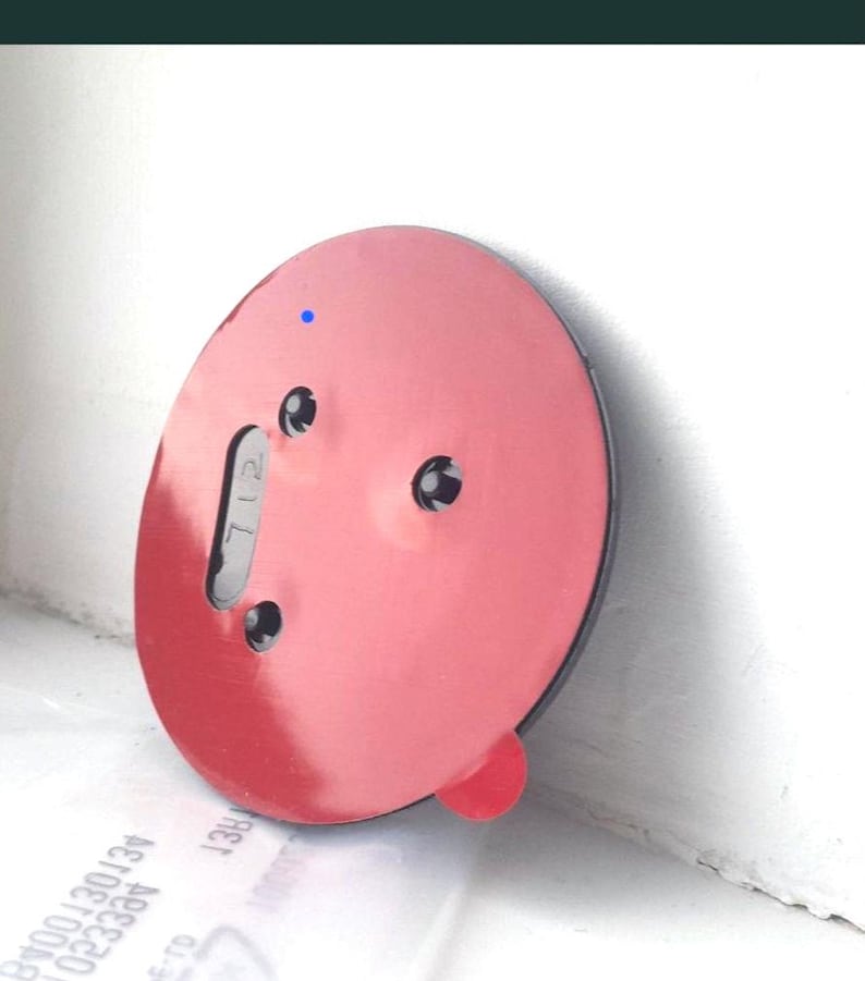 May include: A round, red suction cup with a black rim and three small holes. A small, red tab is visible on the side. The number "712" is printed on a gray tab. A small blue dot is visible on the surface.
