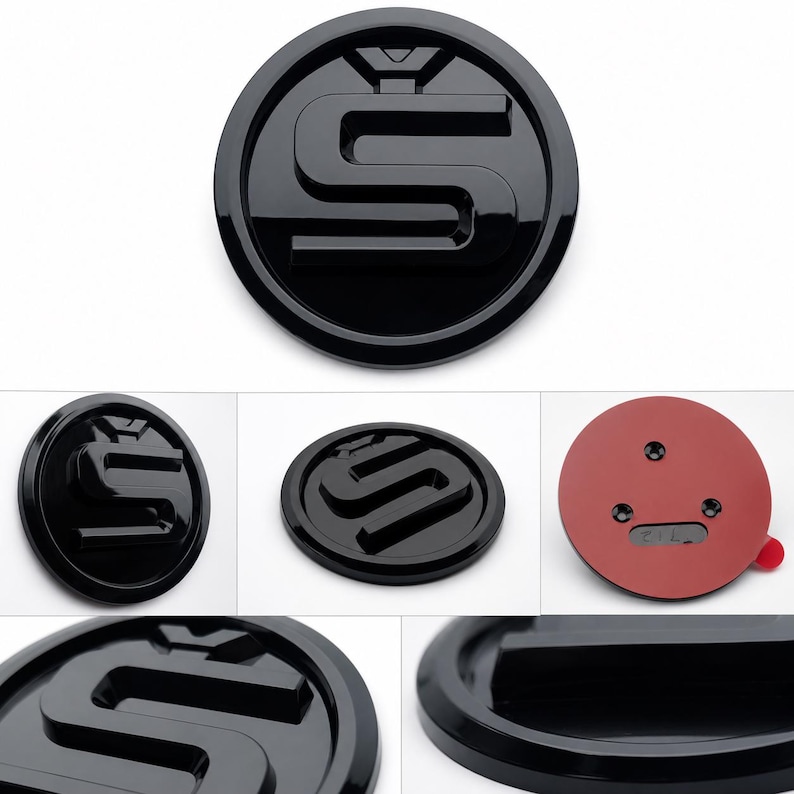 Może przedstawiać: Błyszczący czarny emblemat z podniesionym, stylizowanym wzorem "S" w okrągłej ramie. Emblemat ma gładką, odblaskową powierzchnię i czerwone samoprzylepne podłoże. Prawdopodobnie jest to akcesorium samochodowe.