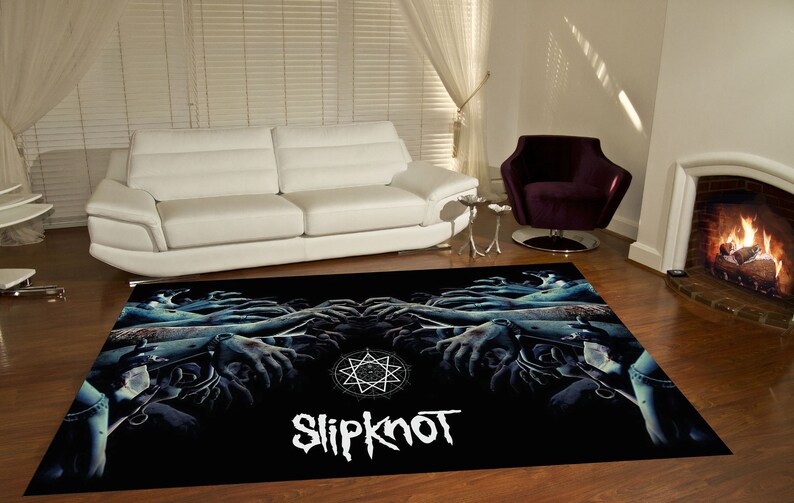 May include: Black and blue rug with a graphic of hands reaching up towards a star and the word "Slipknot" in white.