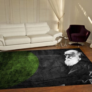 Puede incluir: Una alfombra negra y verde con una cita de Charles Darwin y un retrato de él. La cita dice "Tenía una teoría...", y el retrato está en blanco y negro.
