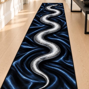 Puede incluir: Una alfombra de pasillo rectangular larga que presenta una serpiente plateada metálica con escamas detalladas que se enrosca en forma de S sobre un fondo azul marino oscuro que imita la apariencia de tela drapeada y plegada con sombras.
