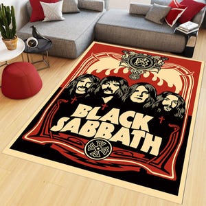 May include: A rectangular area rug featuring a graphic illustration of the band Black Sabbath. The design includes four figures with long hair, the text Black Sabbath in large cream letters, and red, black, and cream decorative border elements.