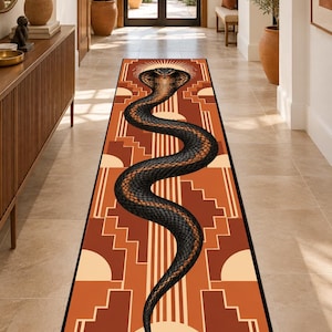Peut inclure: Un long tapis de couloir rectangulaire orné d'un cobra noir central au motif d'écailles texturé. Le fond présente un design géométrique dans des tons orange brûlé, terre cuite et crème, avec un motif en rayons de soleil derrière la tête.