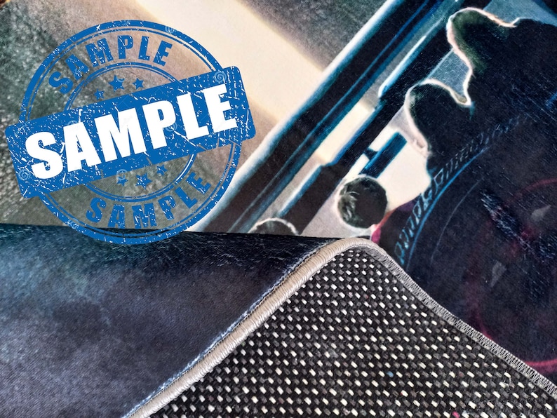 May include: A close-up of a blue and white rug with a black and white patterned backing. The rug has a frayed edge and a blue and white sample stamp.