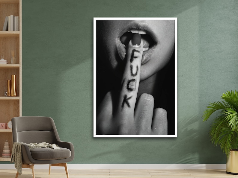May include: Black and white photograph of a person's hand with the word "F.U.C.K." written on the index finger. The finger is placed in front of the person's mouth, which is slightly open.