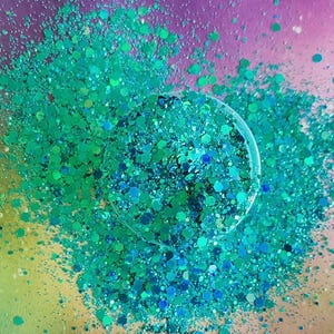 May include: A close-up of teal and blue glitter, with a variety of sizes and shapes. The glitter is scattered on a purple and green background.
