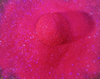 May include: A close-up of a pink sparkly surface with a round, pink, sparkly object in the center.