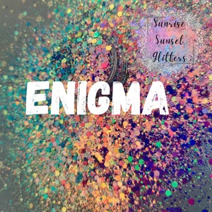May include: A close-up of a jar of colorful glitter with the word "ENIGMA" in white letters on top. The jar is labeled "Sunrise Sunset Glitters".