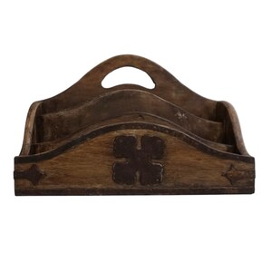 May include: A wooden desk organizer with a handle and multiple compartments. The organizer is stained a medium brown color and features decorative metal accents. The front of the organizer has a four-leaf clover design.