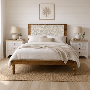May include: A bedroom set featuring a wooden bed frame with a carved headboard and two matching nightstands. The bed is covered with white bedding and a tan throw. A framed tree art piece hangs above the bed, and a jute rug is on the floor.