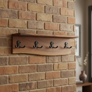 May include: A wooden wall-mounted shelf with four black metal hooks. The shelf is made of dark wood and has a natural edge design. It is mounted on a brick wall, providing a rustic aesthetic.