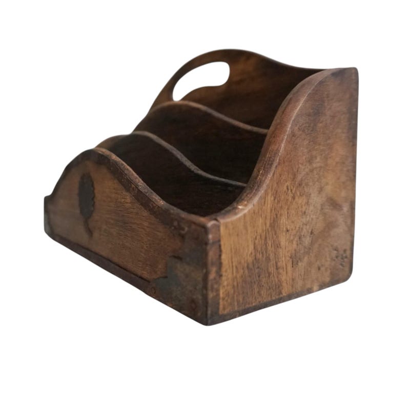 May include: A wooden desk organizer with three compartments and a handle. The organizer is made of dark brown wood and has a curved design. A small tree-like design is visible on the front.