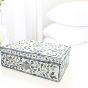 May include: A rectangular decorative box with a floral design in shades of blue and white. The box is made of bone inlay and has a hinged lid.