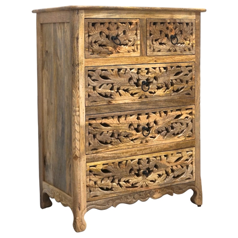 Op de afbeelding: Houten dressoir met vijf lades, twee kleine en drie grote. De lades zijn ingewikkeld gesneden met een bladeren ontwerp. Het dressoir is gemaakt van lichtbruin hout en heeft zwarte metalen handgrepen.