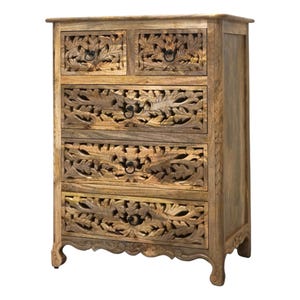 Op de afbeelding: Houten dressoir met vijf lades en een gesneden bloemenontwerp. De kast heeft een lichtbruine afwerking en zwarte metalen handgrepen. De onderkant van de kast heeft gebogen poten.